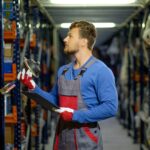 Man inspecting used car parts in a warehouse