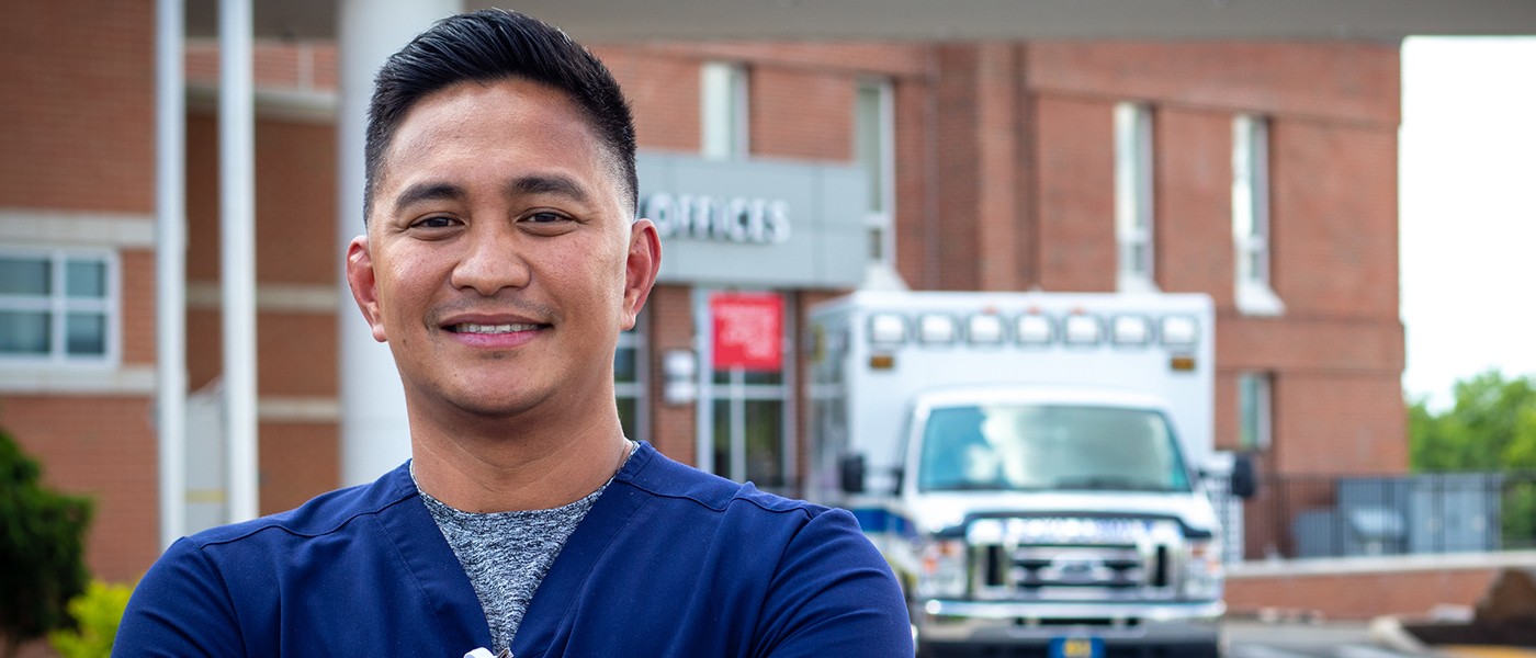 Smiling male nurse standing outside UPMC Muncy hospital showcasing career growth.