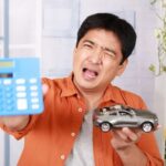 Person Signing Car Loan Documents at Dealership